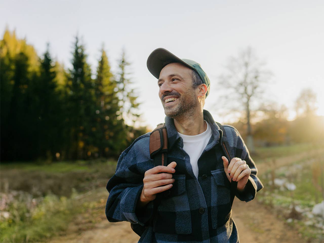 Smiling middle aged white man stands in the evening sun while hiking outdoors