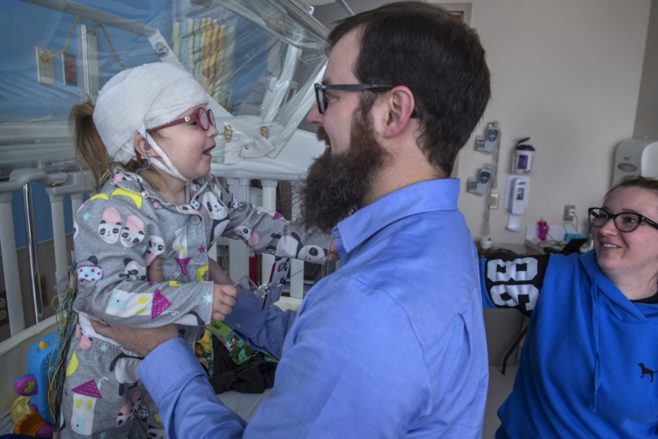 Smiling doctor lifts up young patient