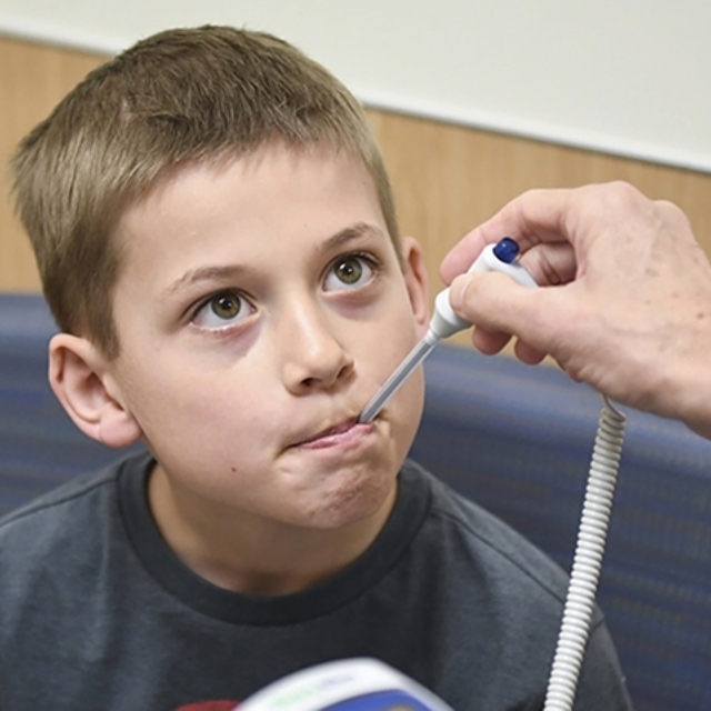 Preteen boy getting temperature taken with thermometer in his mouth.