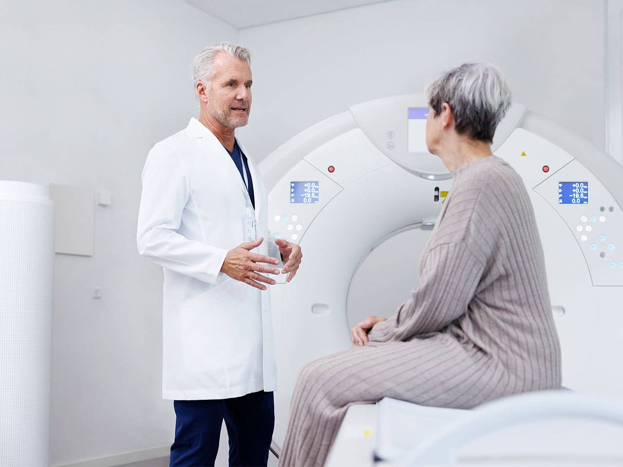 Corewell Health nuclear medicine imaging specialist speaks with a patient as she sits in front of an imaging system
