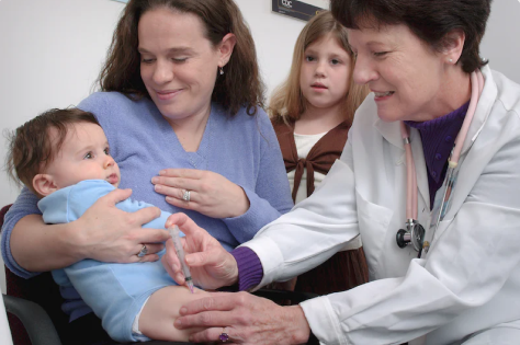 Smiling mom holds a baby while doctor listens to its heartbeat