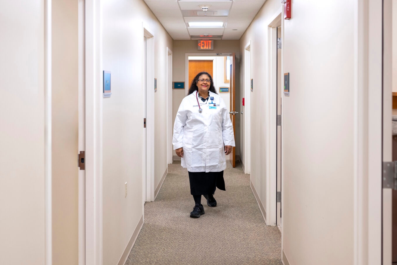 Female doctor in white lab coat walking down a hallway