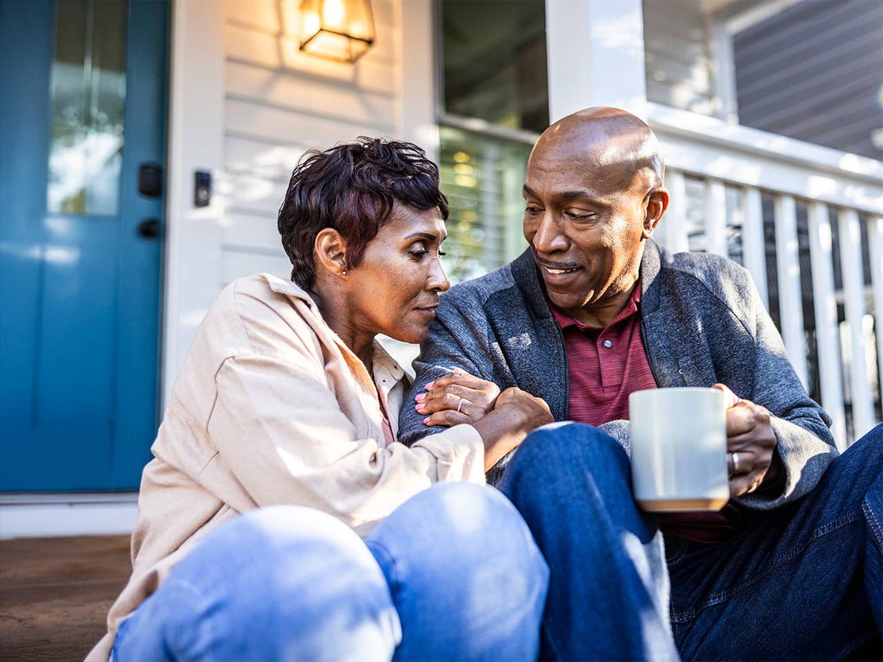 Elderly Black man sits next to his wife on the front step of their house