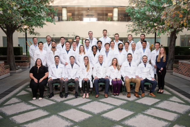 Medical students and faculty members pose together for a group photo, smiling and dressed in professional attire.