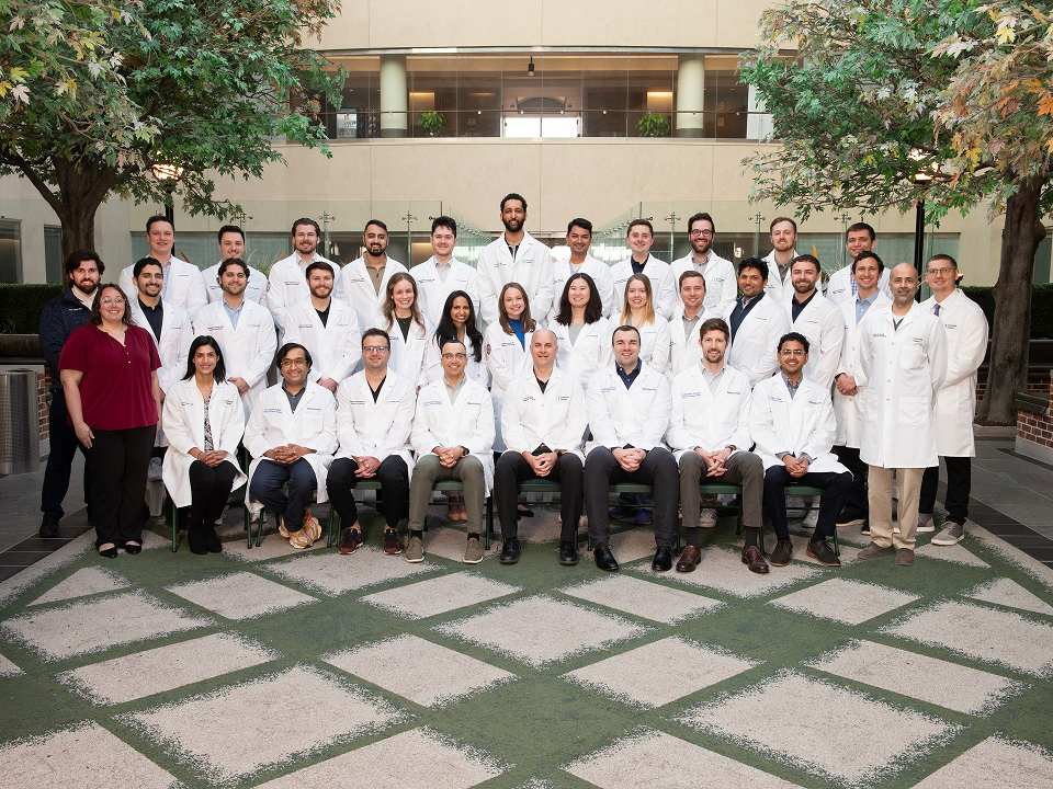 Medical students and faculty members pose together for a group photo, smiling and dressed in professional attire.