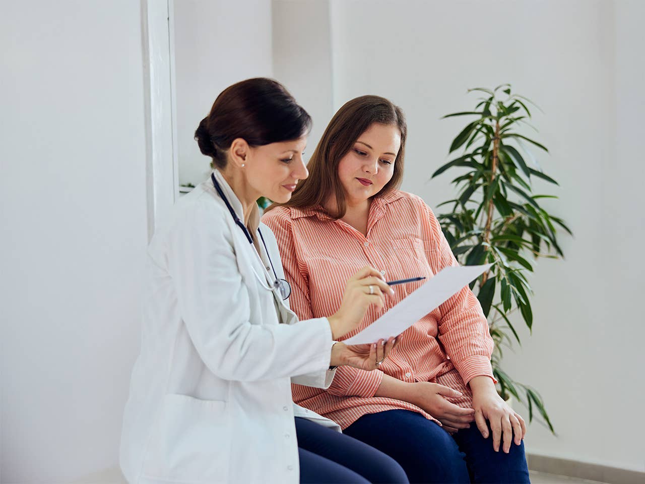 Woman in a pink shirt sits next to a nutrition counselor as they discuss treatment plans