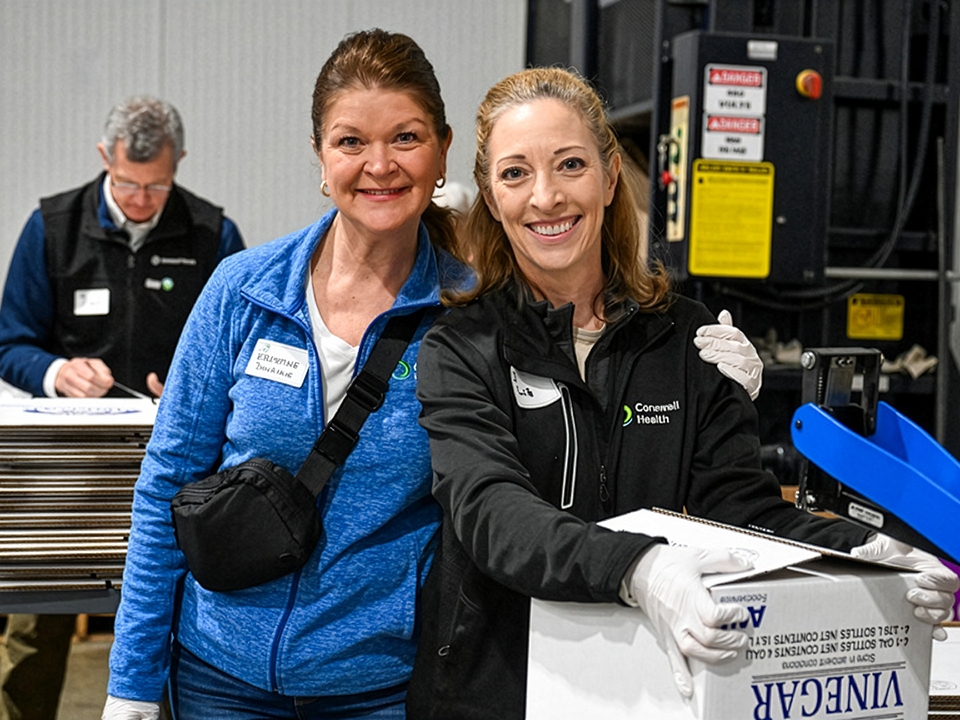 Two women standing side by side in a spacious warehouse, surrounded by shelves and boxes.