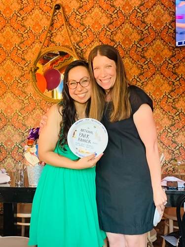 Two women stand together, proudly holding a plaque, symbolizing commitment to wellness in the Beaumont fellowship program.