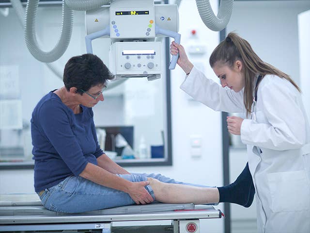 Corewell Health imaging specialist positions an X-ray machine over the leg of a patient