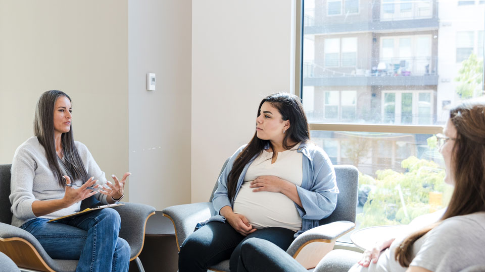 Group of pregnant women sit and speak with each other in a group