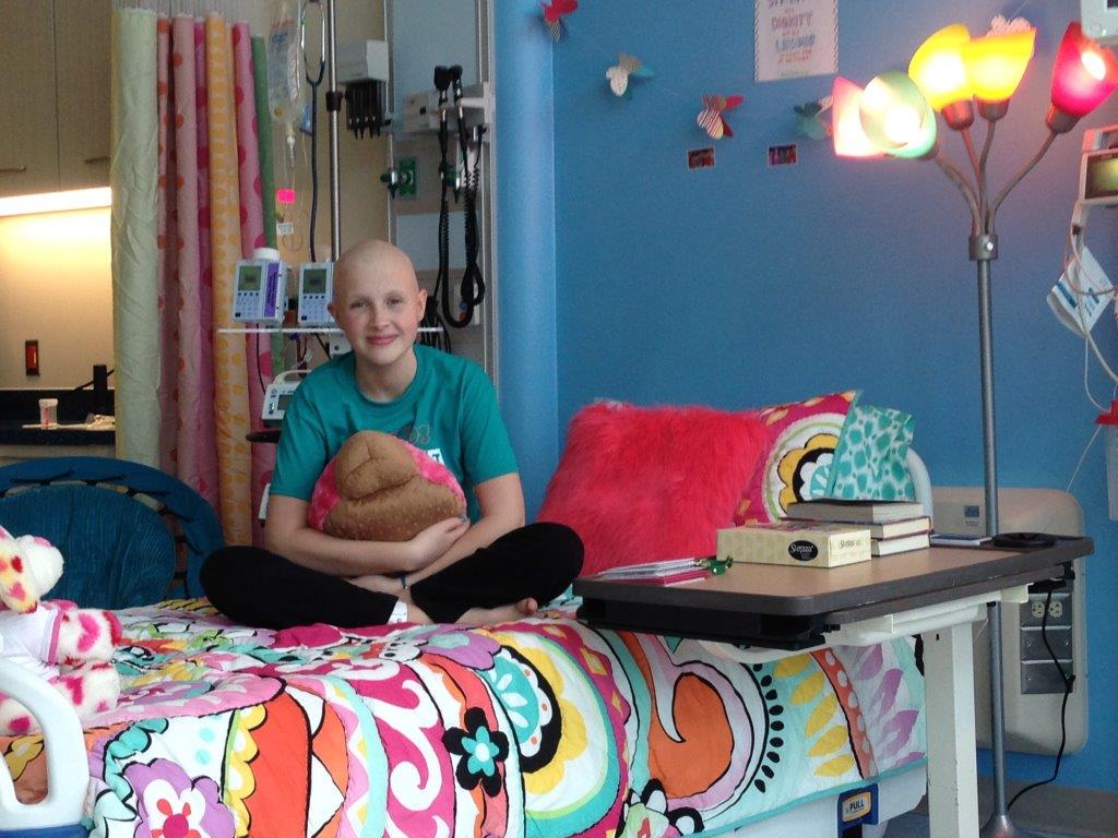 young girl sitting in hospital bed smiling at the camera