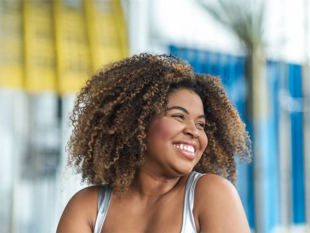 Smiling Black woman with curly hair looks off in the distance