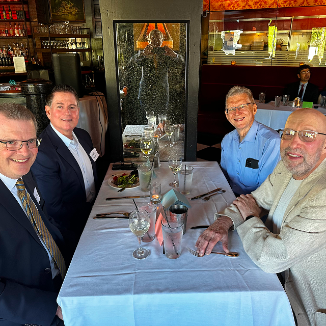 Four attendees seated at a restaurant table during a residency celebration dinner