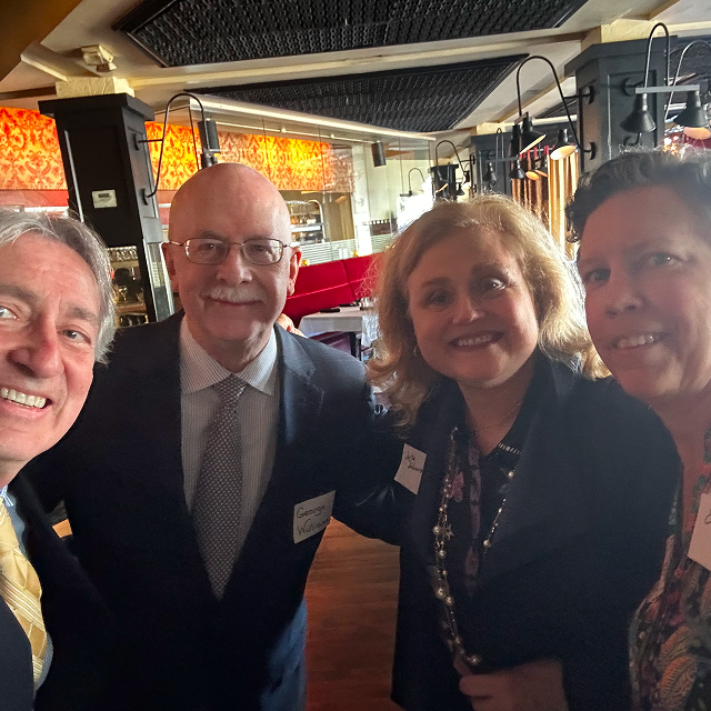 Four attendees posing together for a group photo during a residency celebration dinner