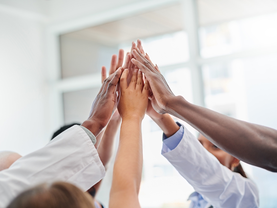 Group of team members putting hands together.