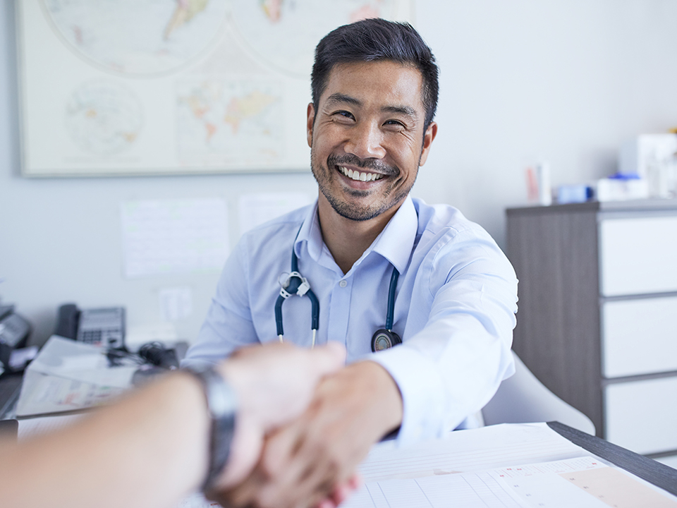 A smiling doctor shakes hands with a patient, conveying a sense of trust and professionalism.