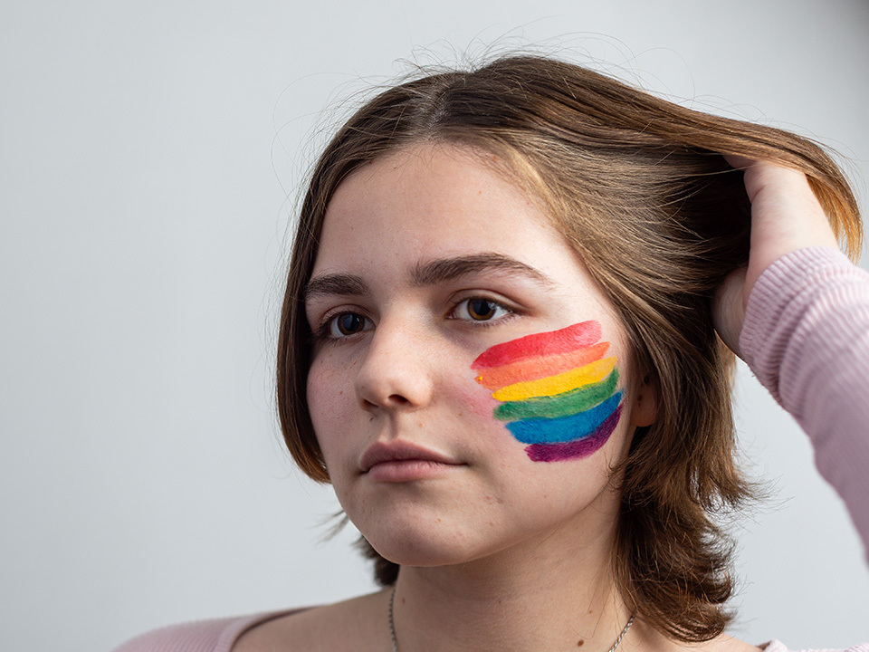 Teenage girl with rainbow painted on her cheek