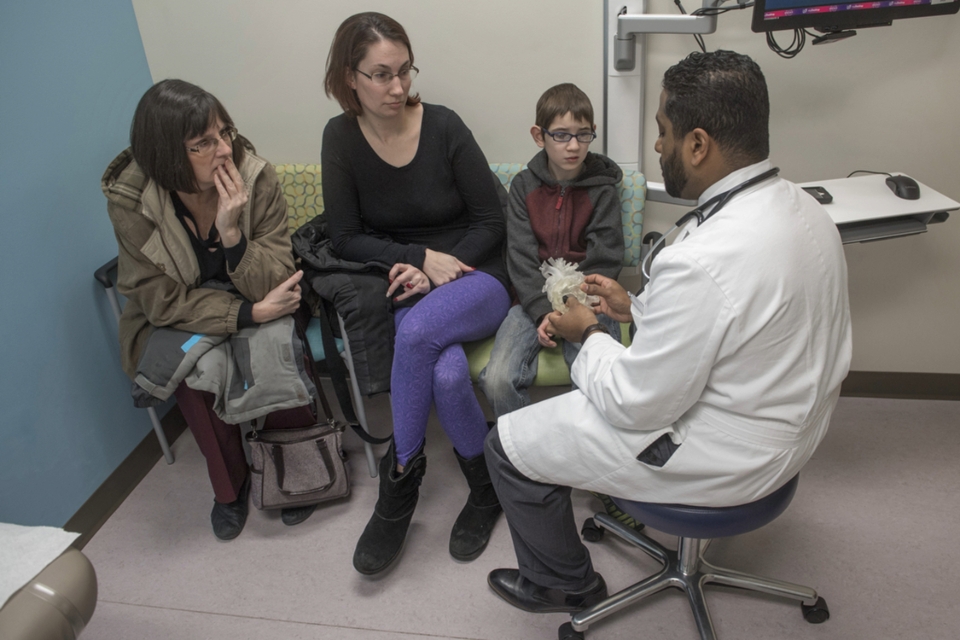 Three people sitting in front of healthcare provider with anatomical model.