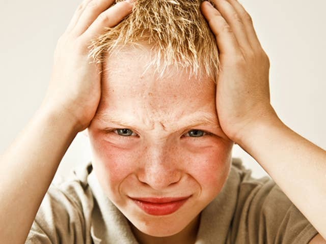 Boy holding his head because he has a headache.