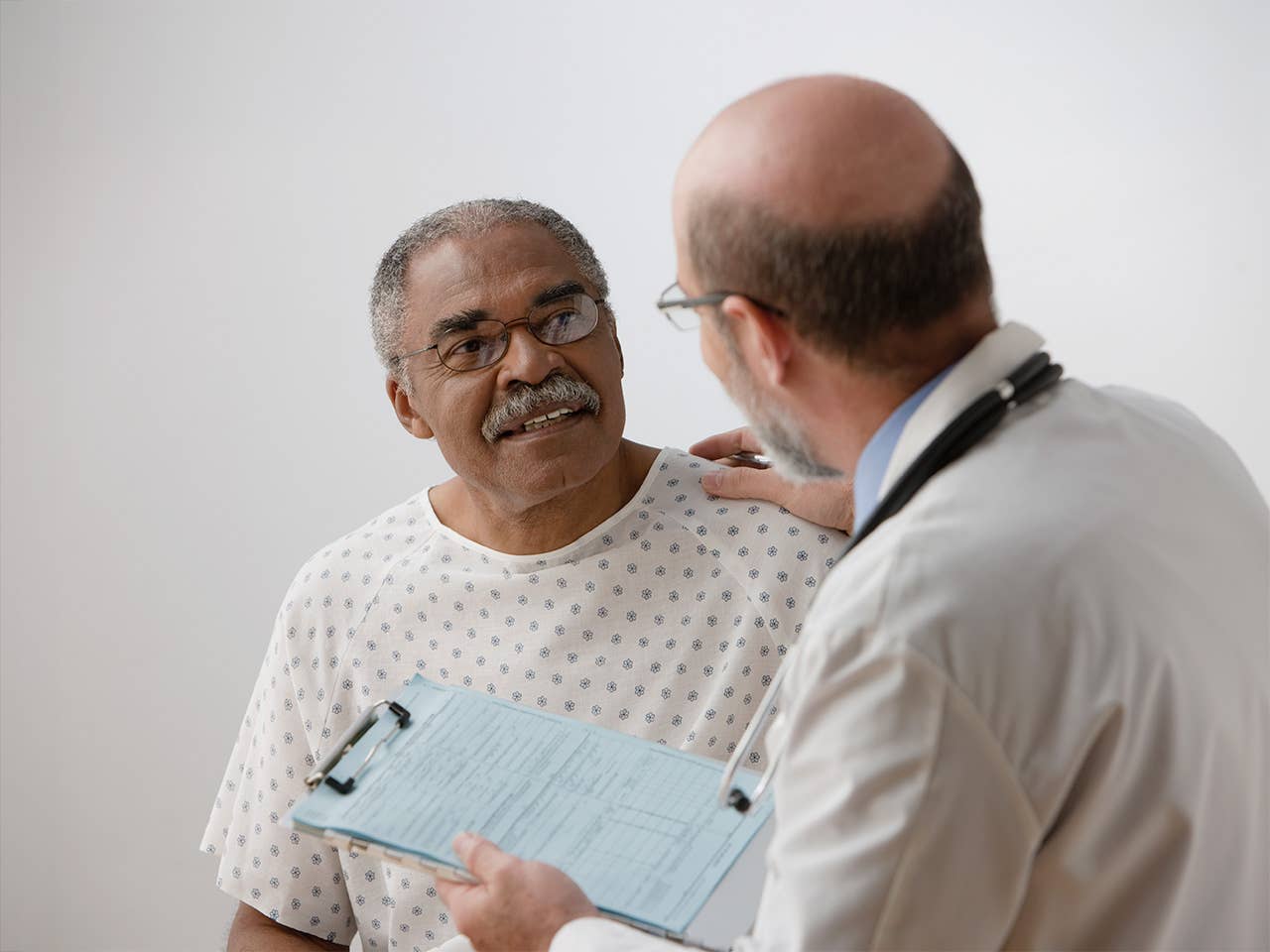 Black man with glasses speaks with a Corewell Health cancer care specialist in an exam room