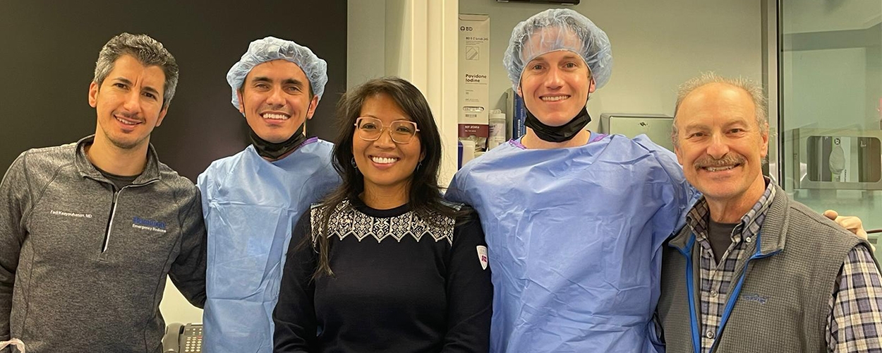 A group of healthcare professionals in surgical scrubs smiling for a photo, showcasing teamwork and education in medicine.
