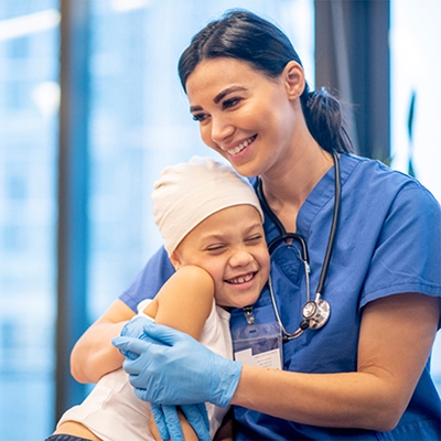 Woman in blue scrubs puts arms around smiling child