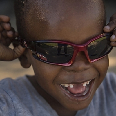 Young Black boy smiling while wearing red sunglasses