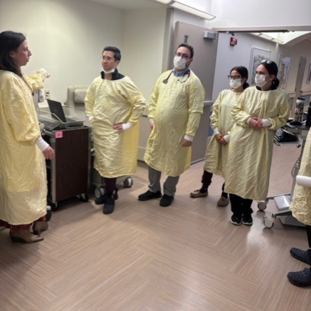 Fellows and staff members dressed in surgical uniforms having a conversation in the hospital hallway