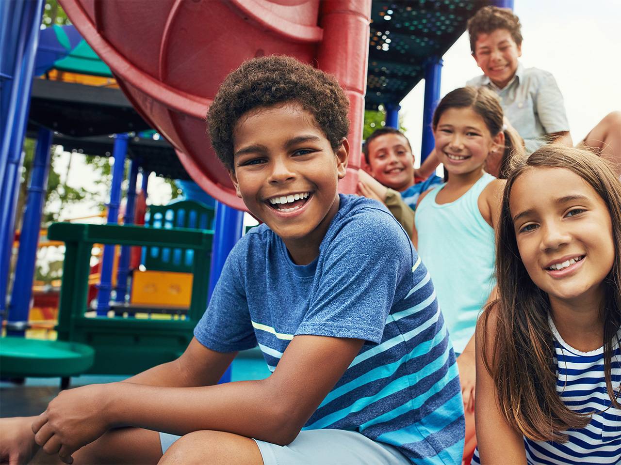 Children playing together on a playground, climbing and sitting near slides during outdoor recreation and social activity.
