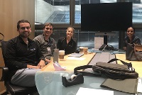 A diverse group of individuals engaged in discussion around a conference table in an office setting during simulation activities.