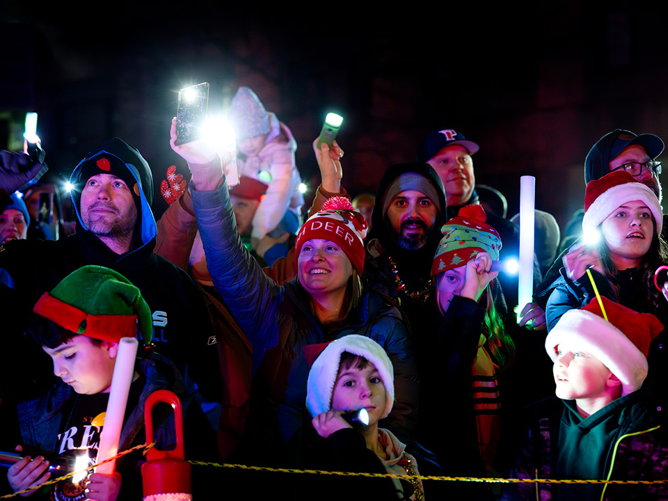Moonbeams for Sweet Dreams event at Corewell Health Children's in Southeast Michigan, a group of adults and children with flashlights in the dark, supporting pediatric patients
