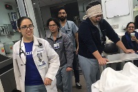A group of individuals engaged in simulation activities within a hospital room setting, showcasing teamwork and learning.