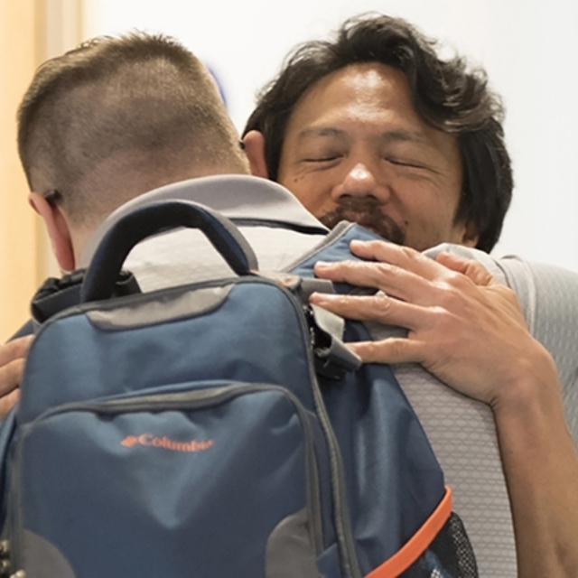 Father wearing a backpack hugs doctor in the neonatal intensive care unit