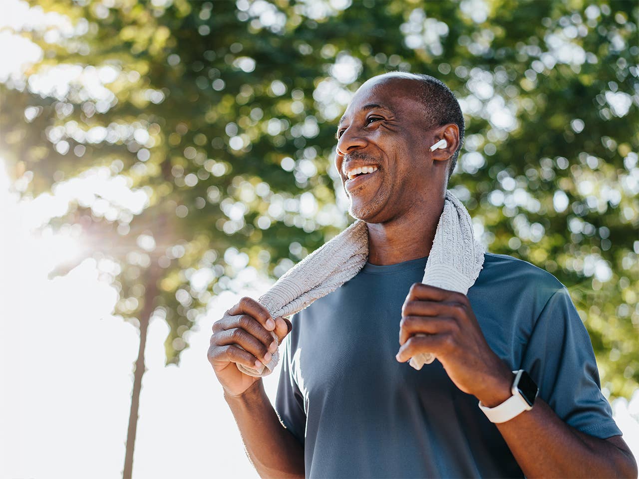 Smiling Black man stands in the sunshine with a towel around his neck after exercising