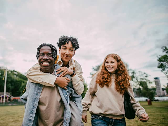 Two teenage boys and a teenage girl standing together outdoors
