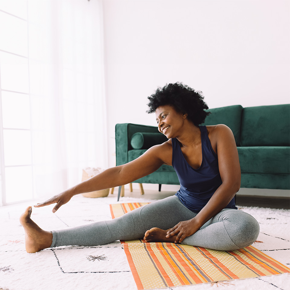 Black woman wearing workout attire stretches her leg