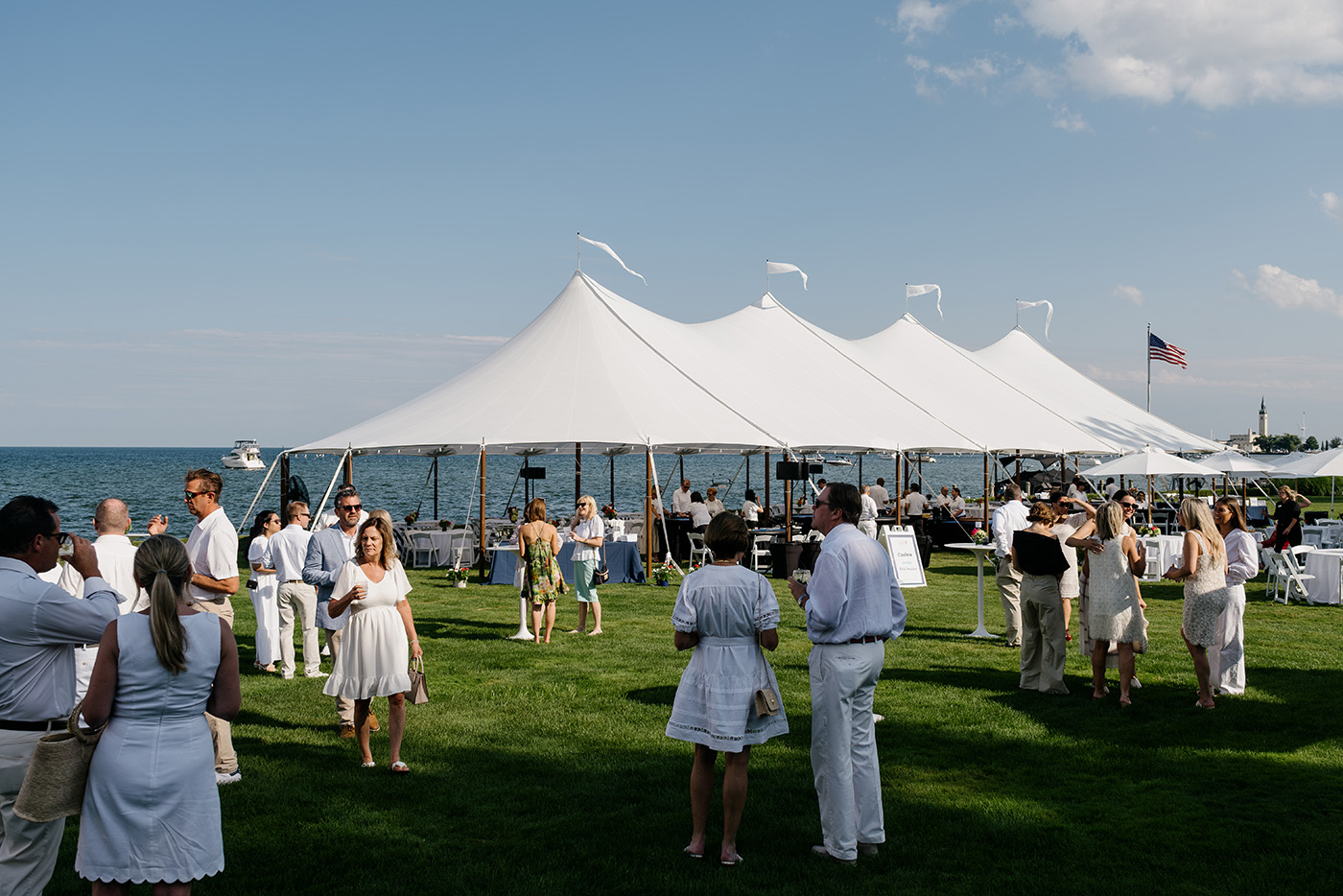 People sitting at tables under tents at the Grosse Pointe Gathering