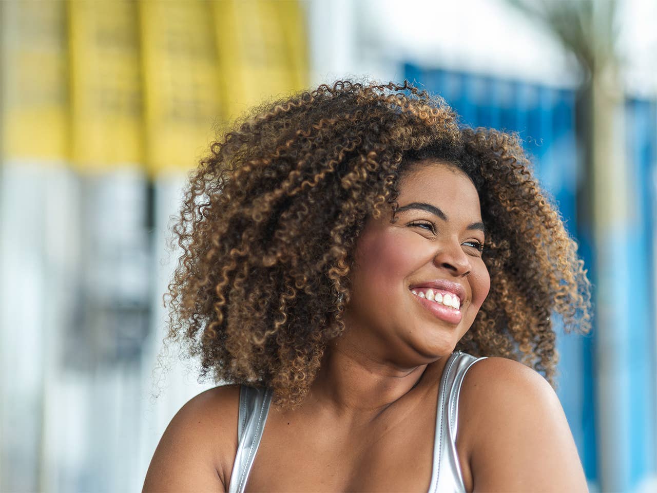 Smiling Black woman with curly hair looks off in the distance