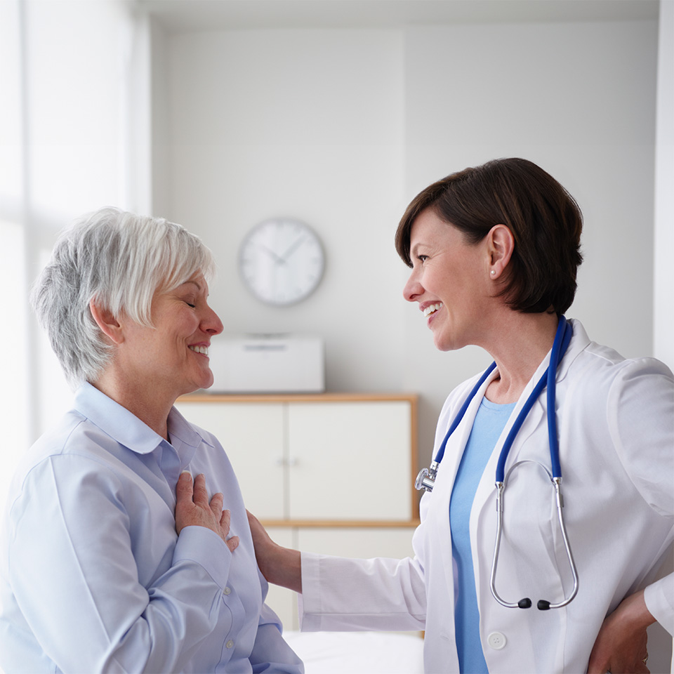 Smiling female doctor places hand on shoulder of female patient