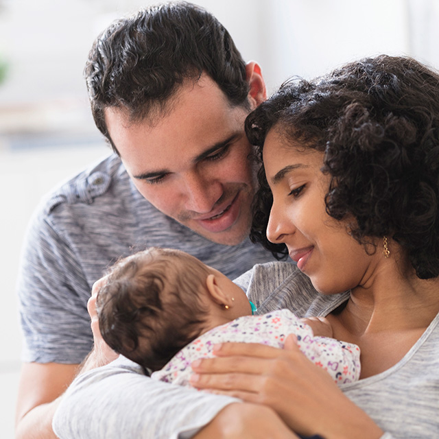 New mother and father lovingly look at their newborn baby together