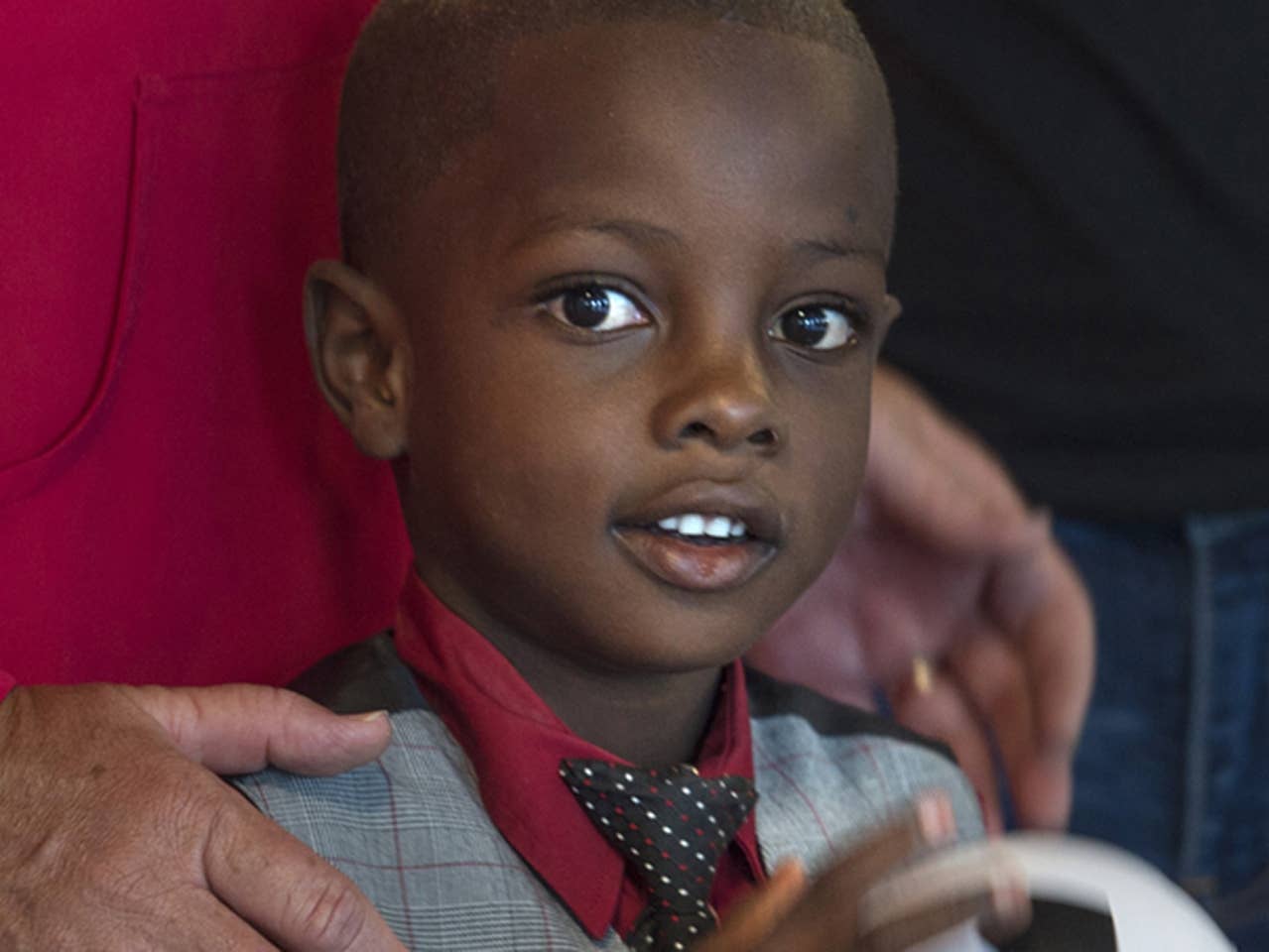 Close-up of smiling boy with adults behind him