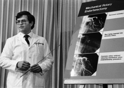 Black and white photo showing a doctor standing near large xrays and talking