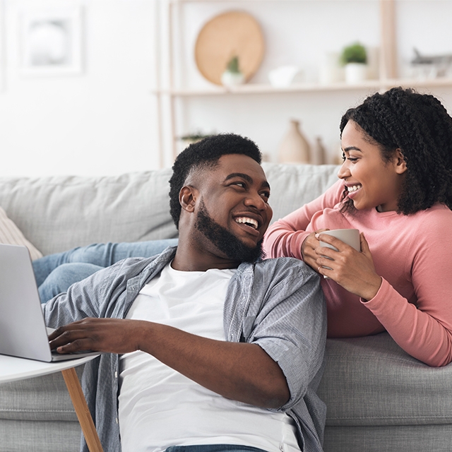 A couple sitting together on a couch, using a laptop to join Corewell Health Lifestyle Medicine support group on Facebook.