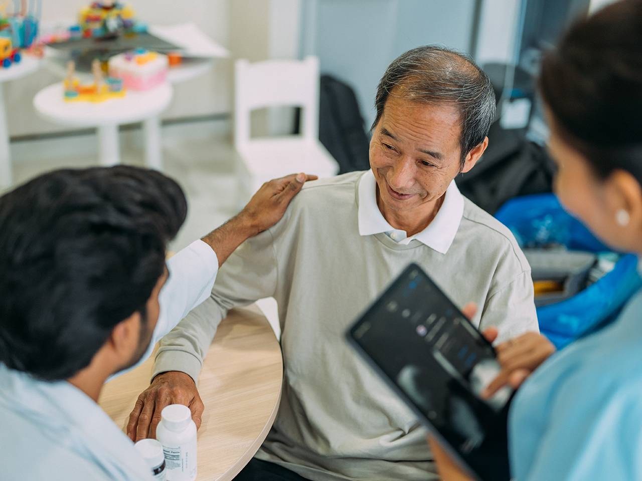 A man speaks with a doctor while a nurse observes the conversation attentively.
