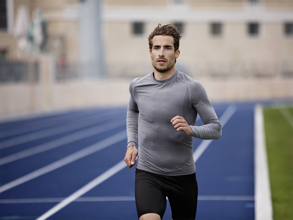 Runner training on a track, representing active recovery and treatment available through orthopedic urgent care.