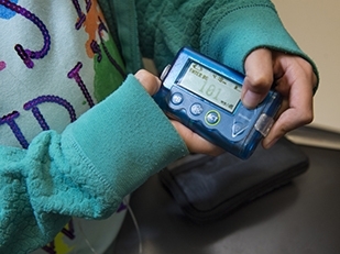 Close up of a child holding an insulin pump