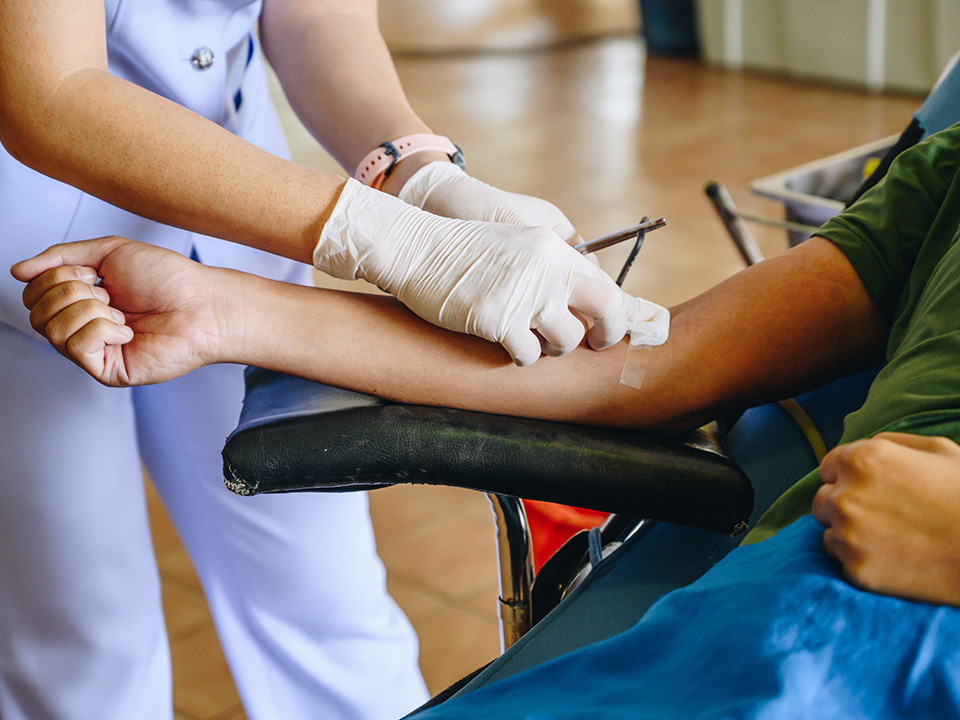 A nurse is administering a blood draw to a patient in a clinical setting.