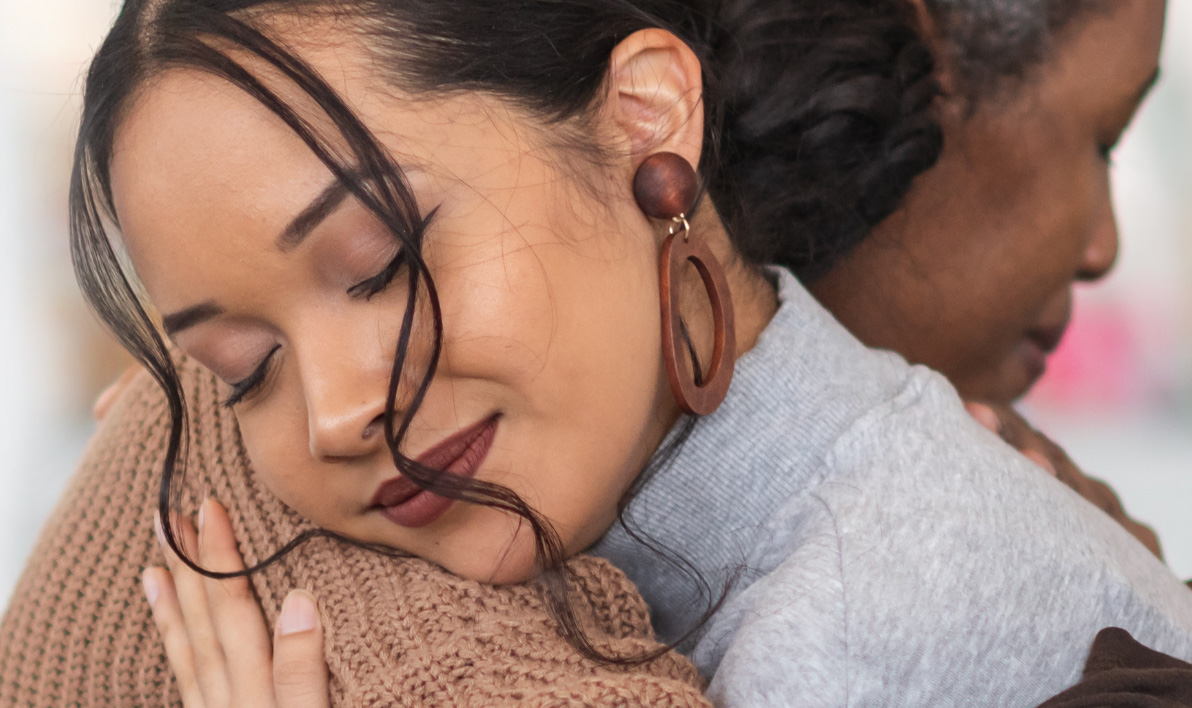 Dark haired women hugging someone else