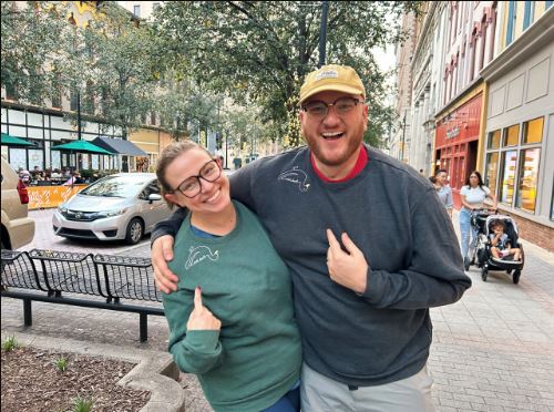 White woman on left and white man on right hug and smile