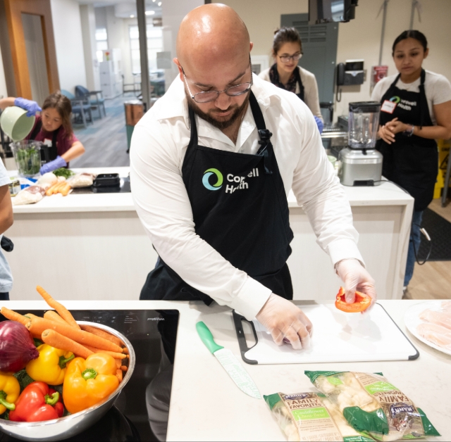 A team member preparing vegetables on a cutting board during a community outreach class